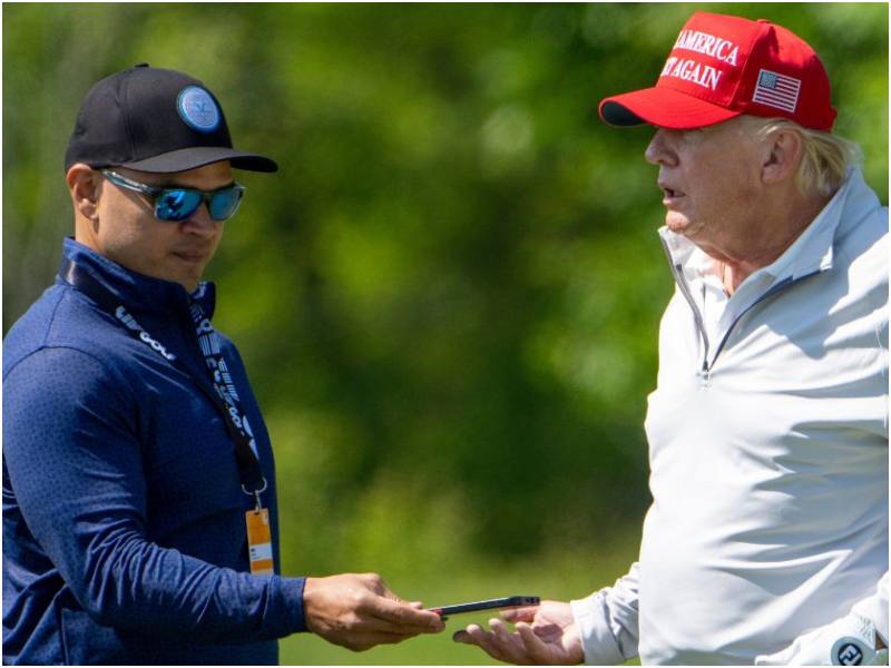 Walt Nauta, left, takes a phone from Former President Donald Trump